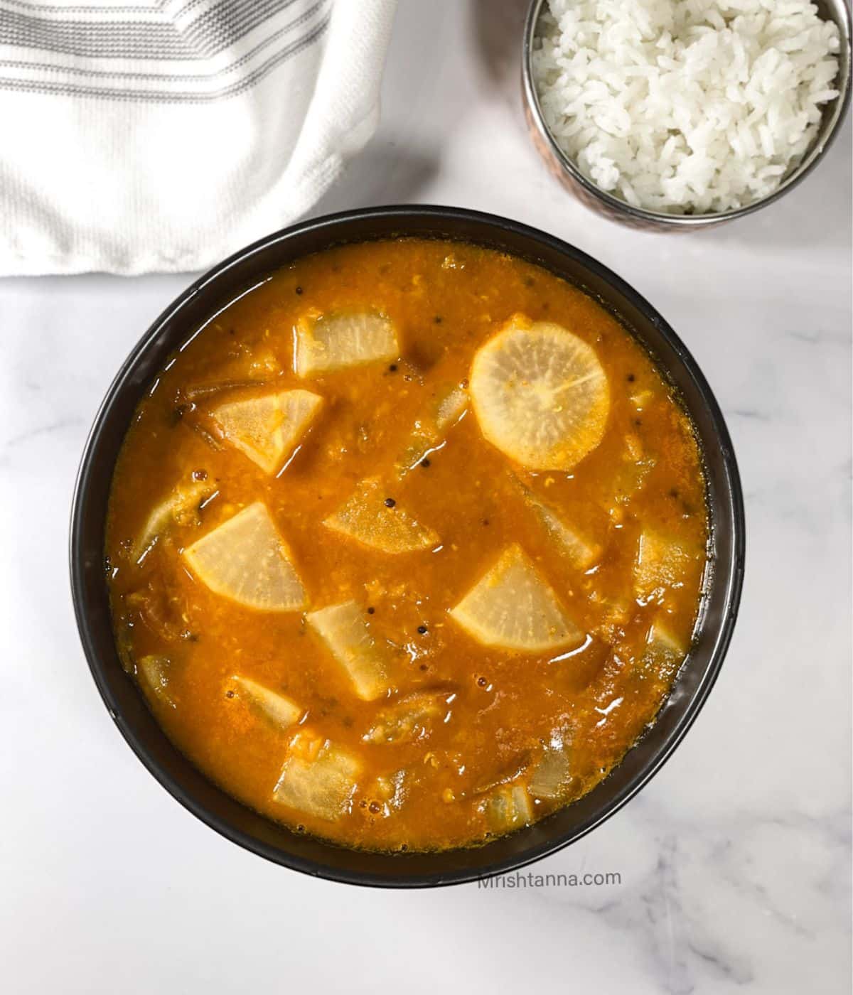 Head shot of bowl with Radish sambar on the table.