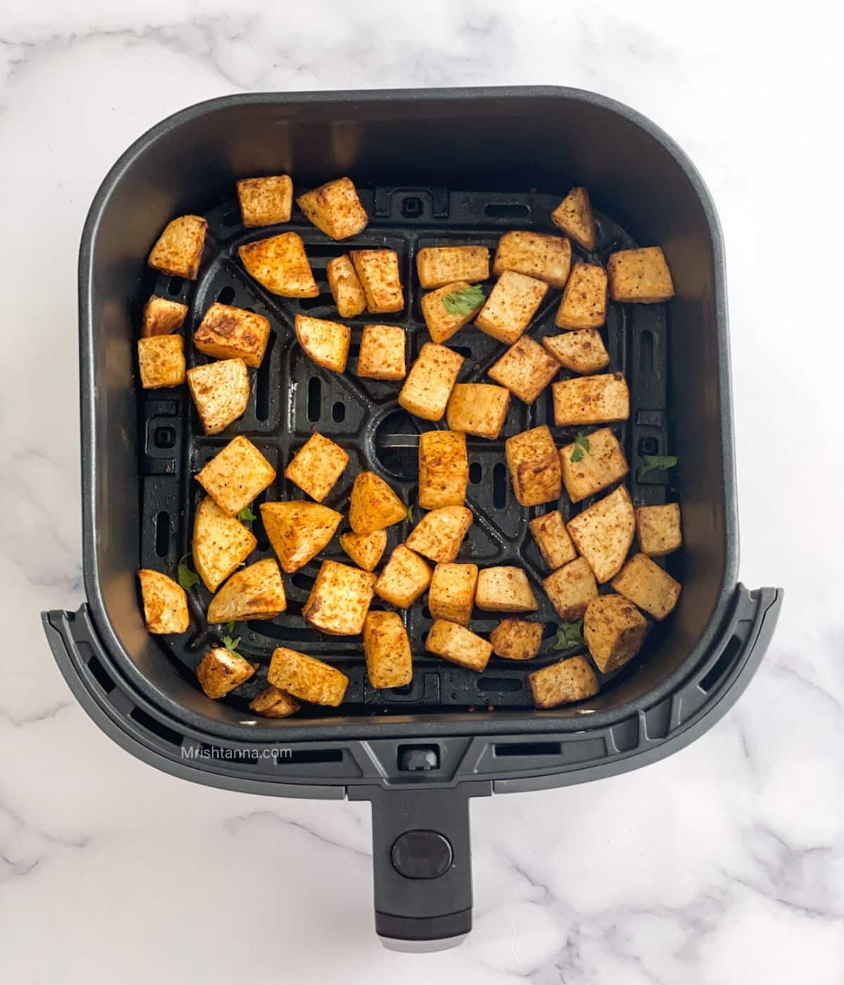 The air fryer basket is with roasted turnips.