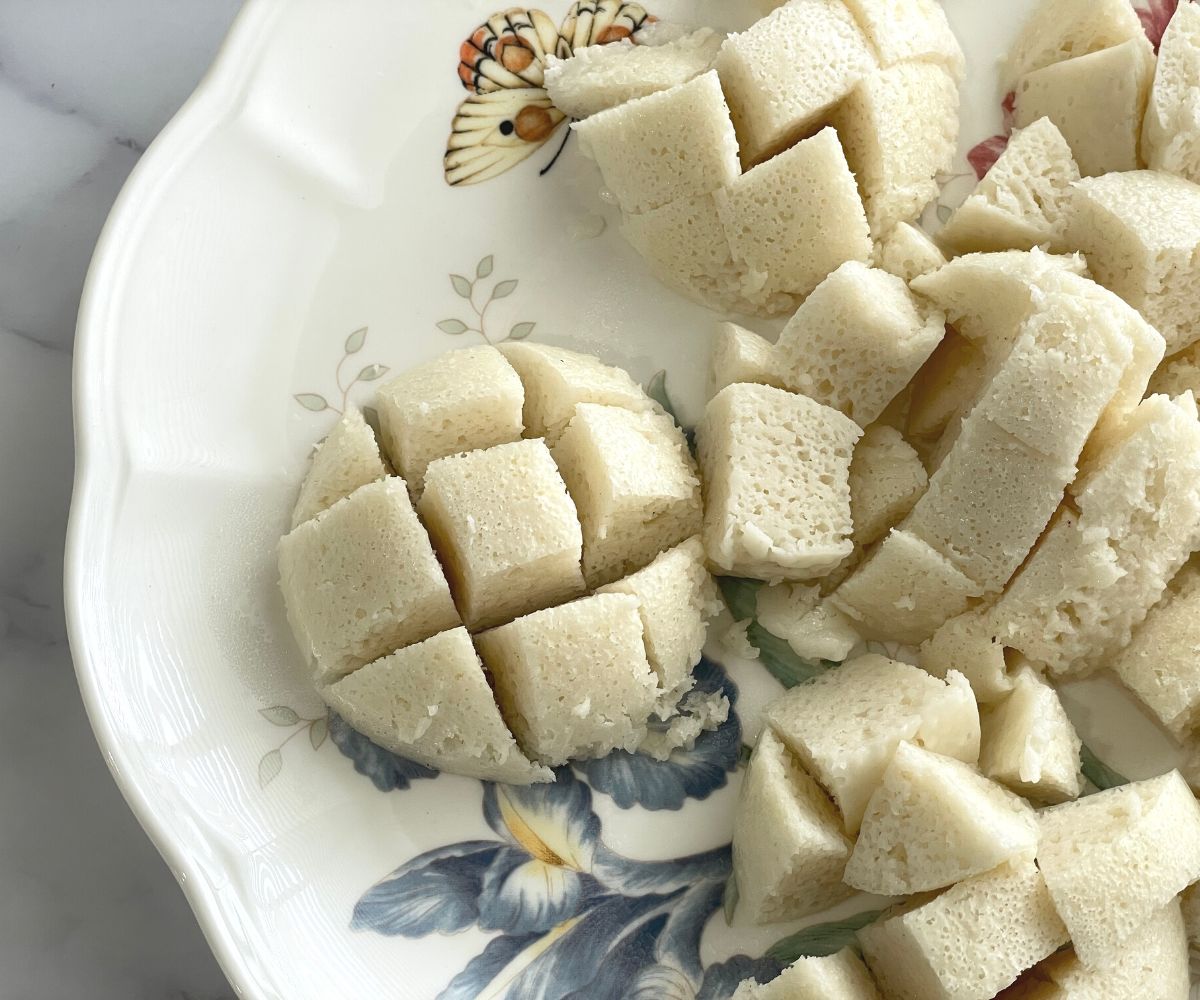 A plate is with steamed idli and chopped into cubes.