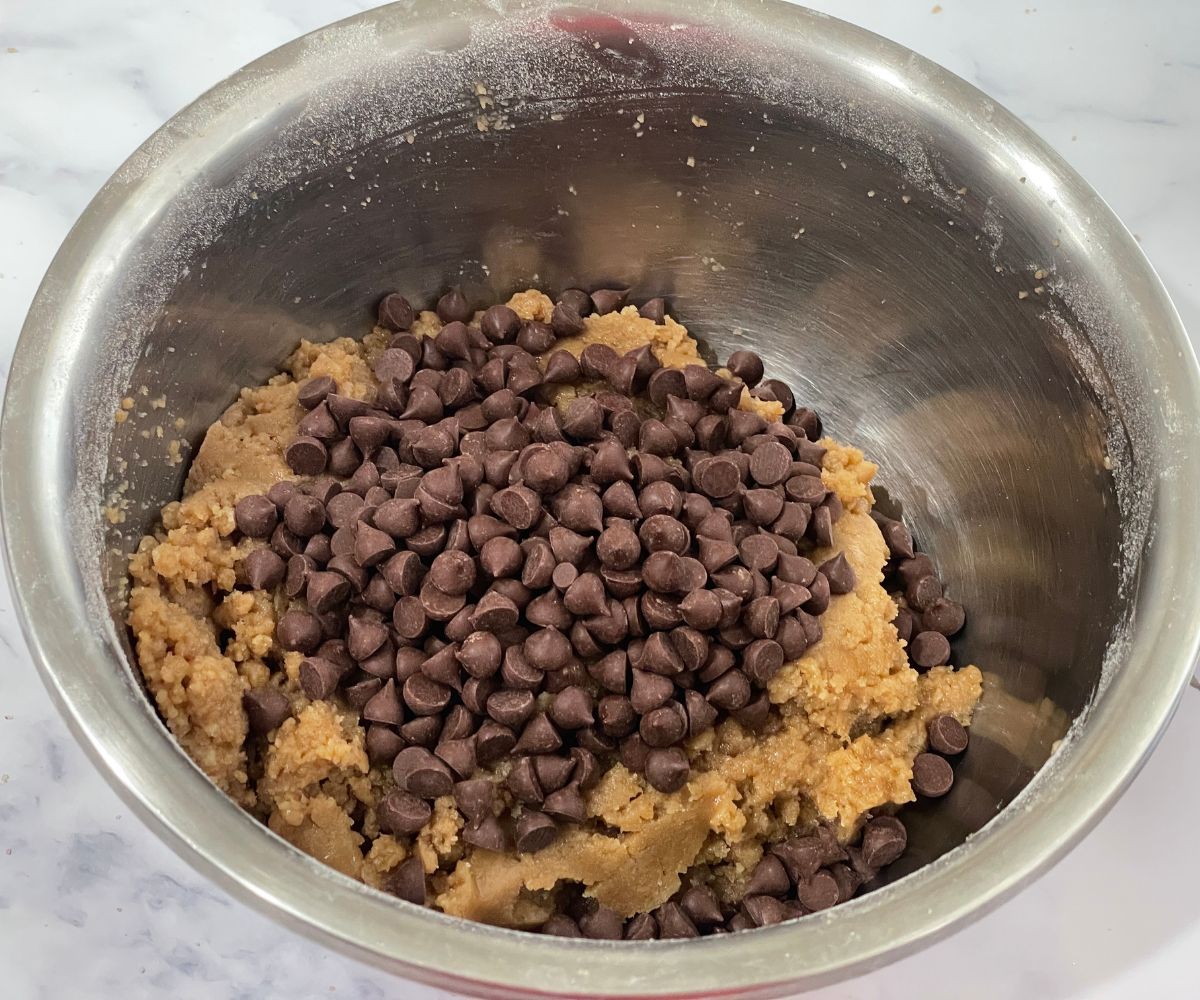 A bowl is with chocolate chip cookie dough on the table.