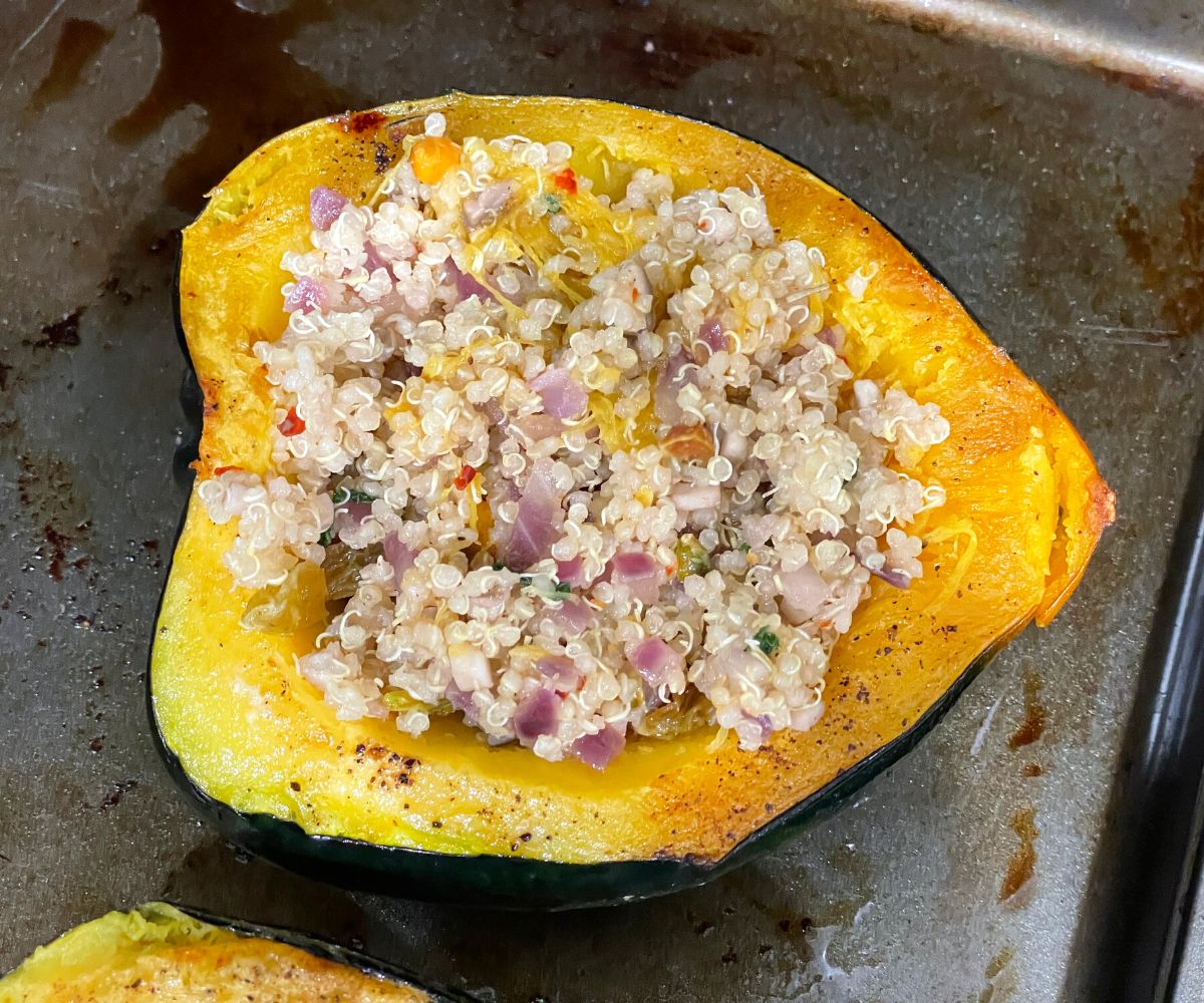 Acorn squash is filled with quinoa stuffing on the baking tray.
