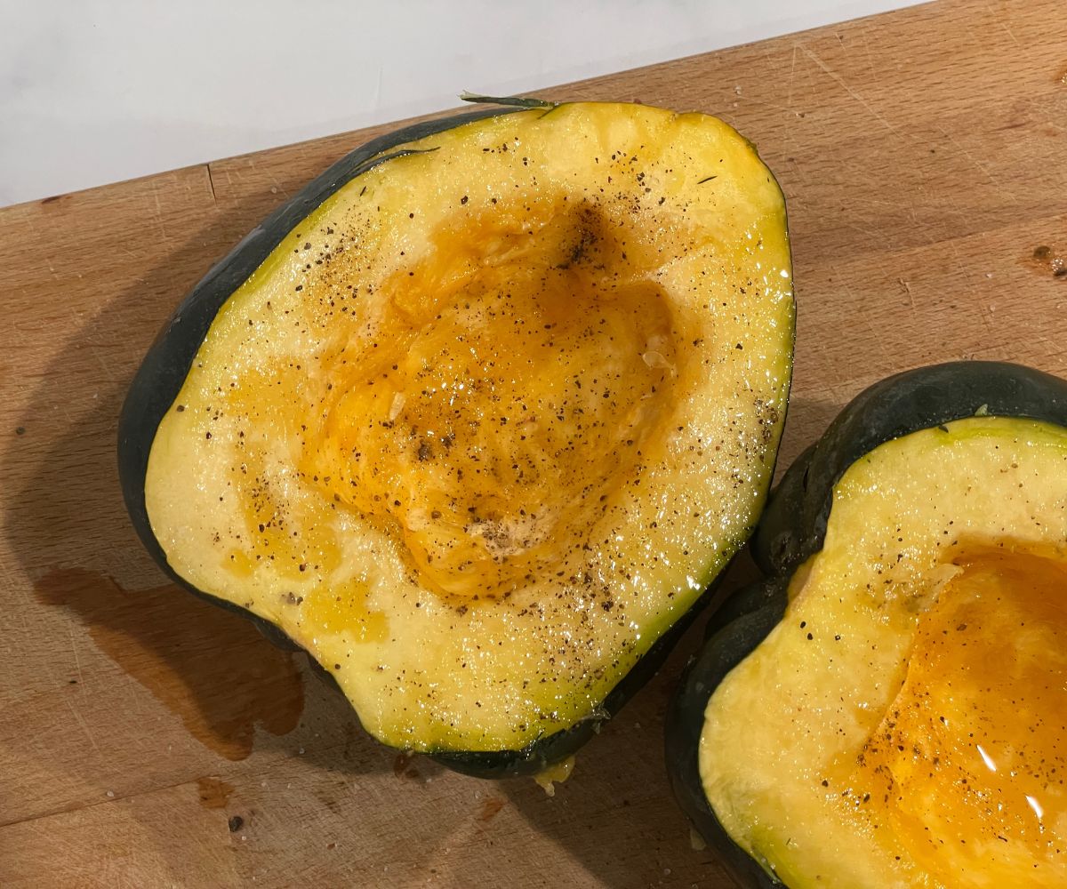 Halved acorn squash is on the chopping board.