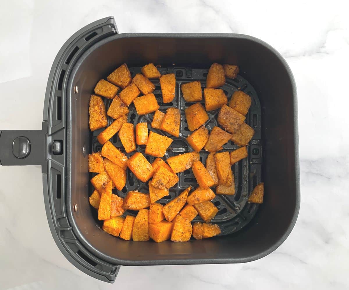 Roasted pumpkin is inside the air fryer basket.