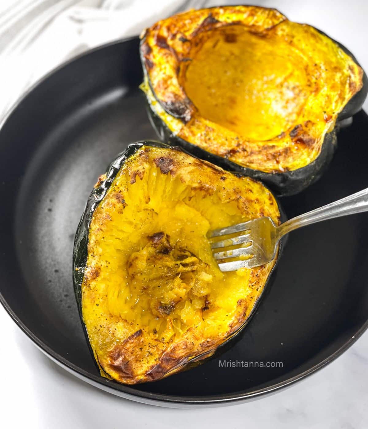 A plate is with air fryer acorn squash and a fork is inserted.