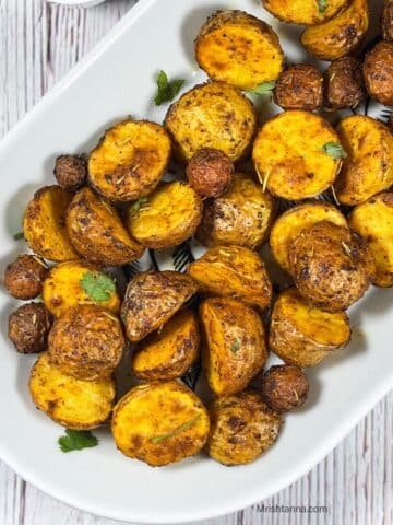 A ceramic tray is with roasted baby potatoes.