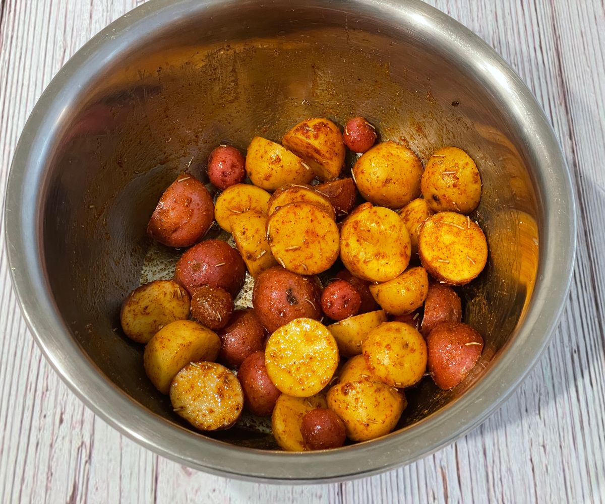 A bowl of baby potatoes is seasoned  on the table.