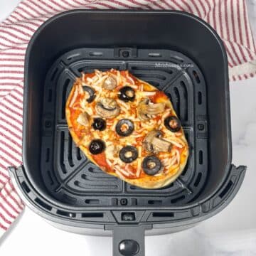 Air fryer basket is with vegan naan pizza.
