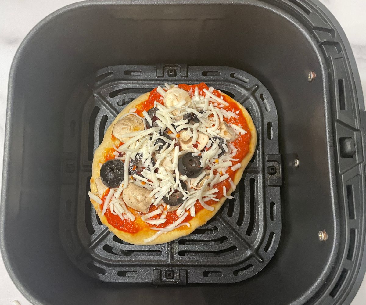 The air fryer basket is with naan pizza.
