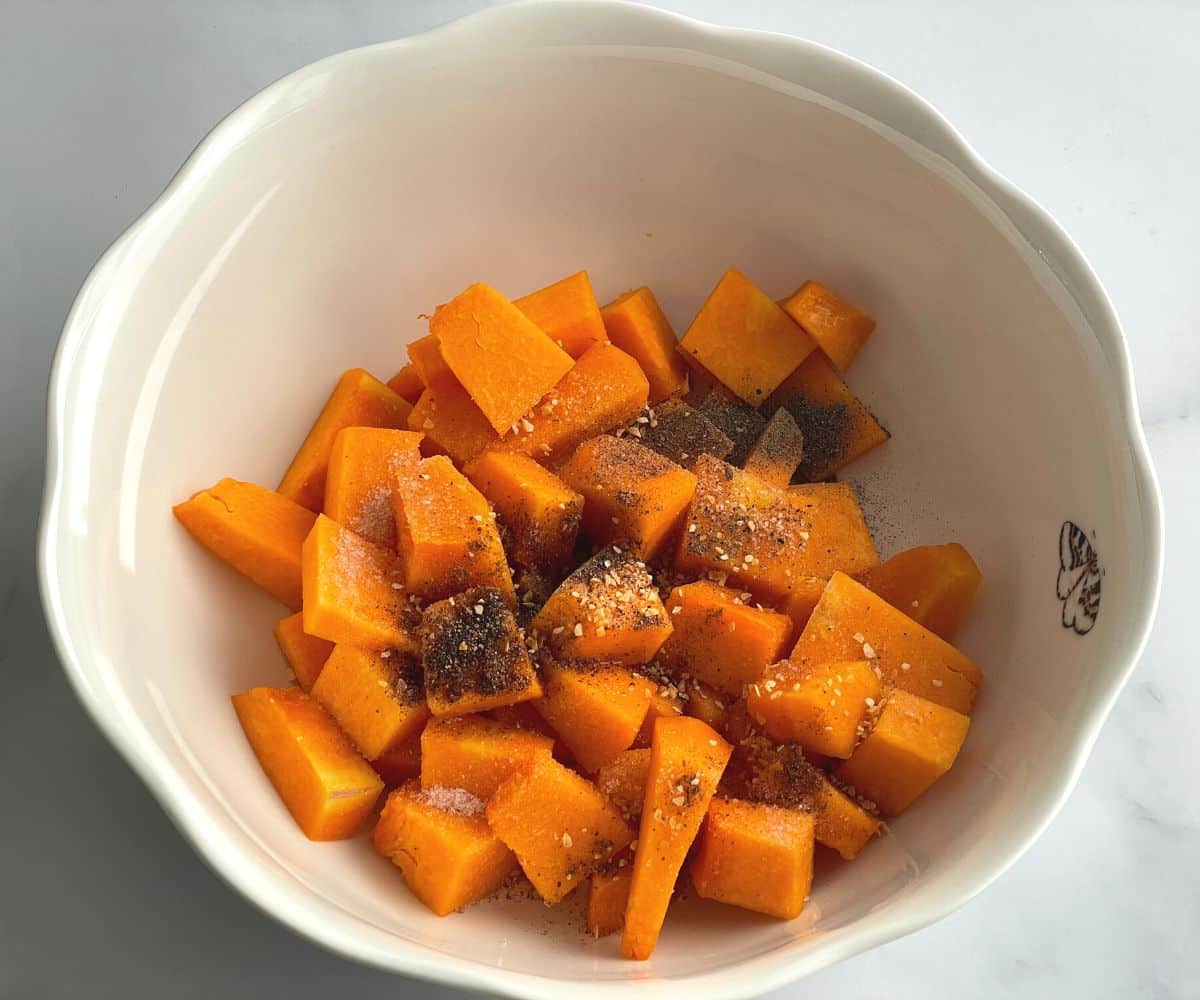 A bowl is with cubed pumpkins and spices.