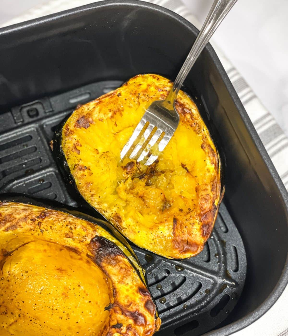 Air fryer basket is with roasted acorn squash.
