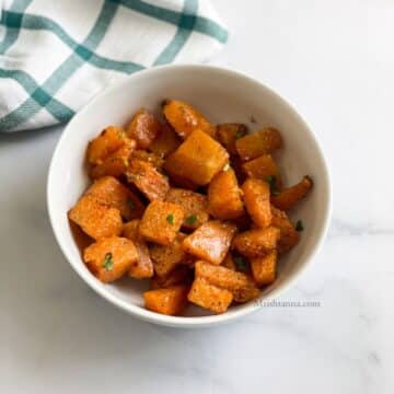 A bowl of roasted pumpkin is on the table.
