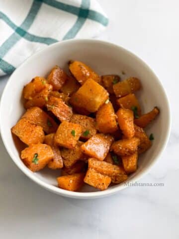 A bowl of roasted pumpkin is on the table.