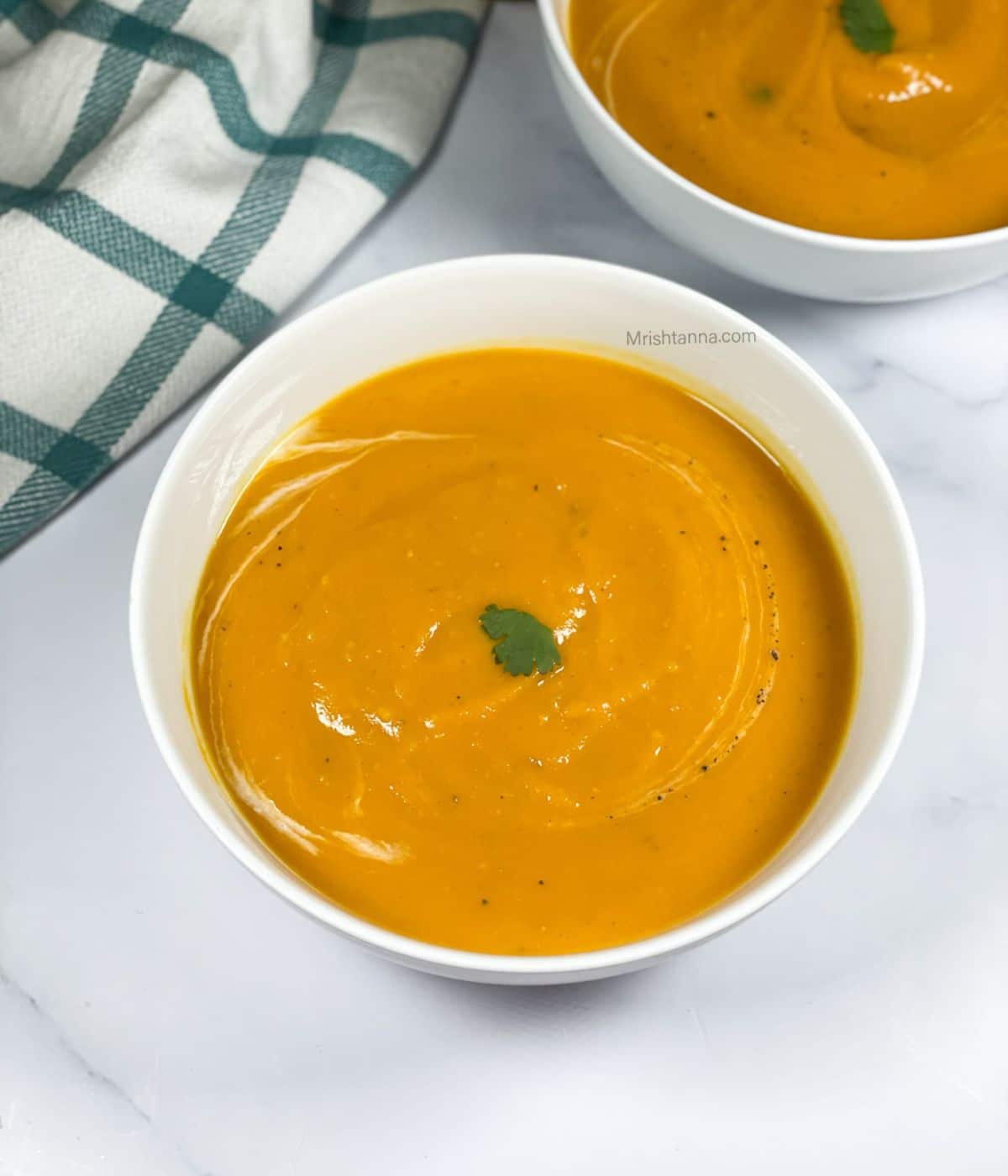 A bowl of butternut squash soup is on the table.