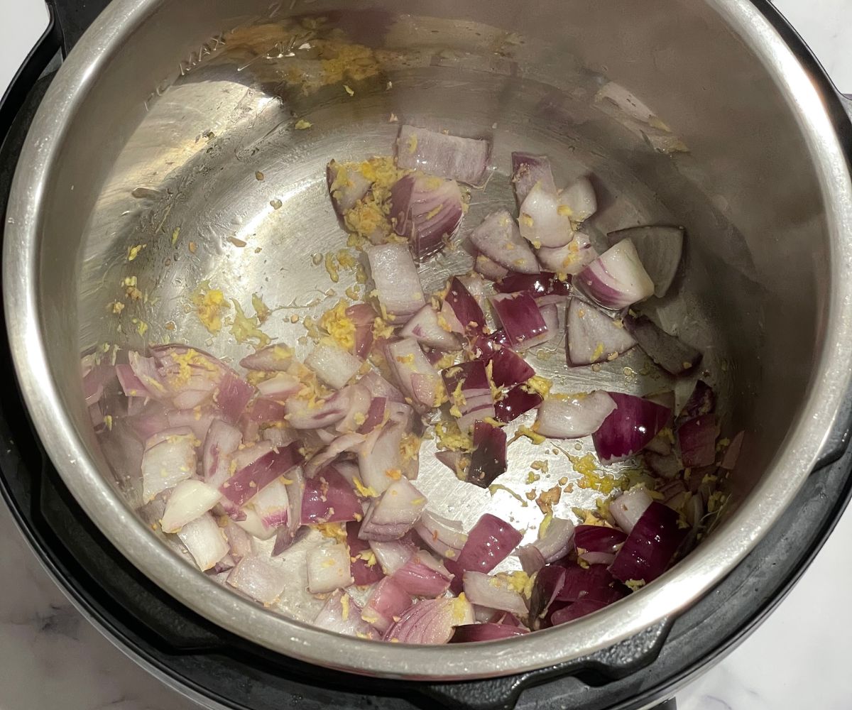 A pot is with sauteed onions, ginger and garlic.