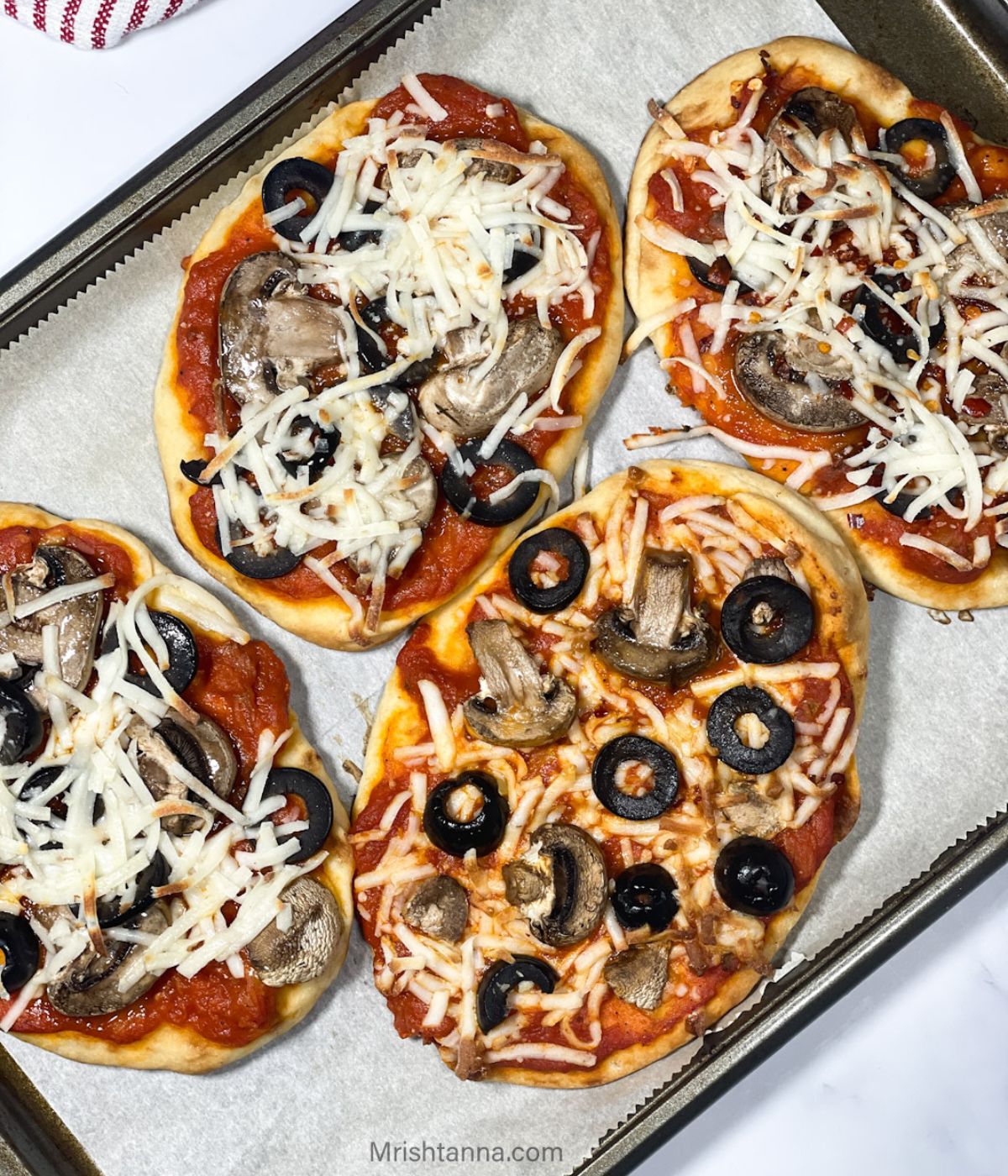 A baking tray is with air fryer naan pizza's.