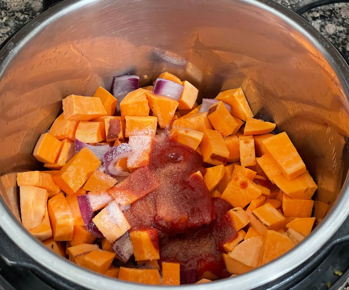 An instant pot is with sweet potatoes, tomato paste and salt on the saute mode.