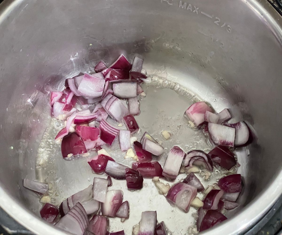 An instant pot is with sauteed garlic and onions.