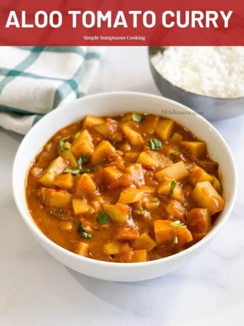 A bowl of potato curry is on the white surface with white rice.