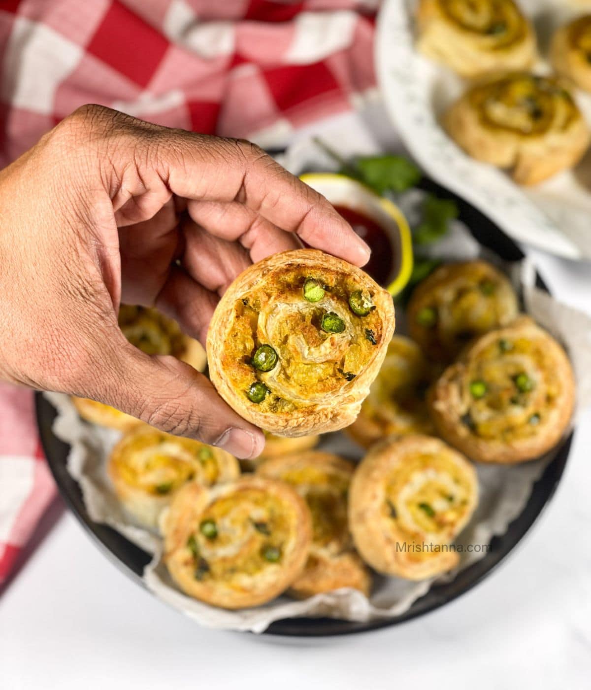 A hand is holding a samosa pinwheel.