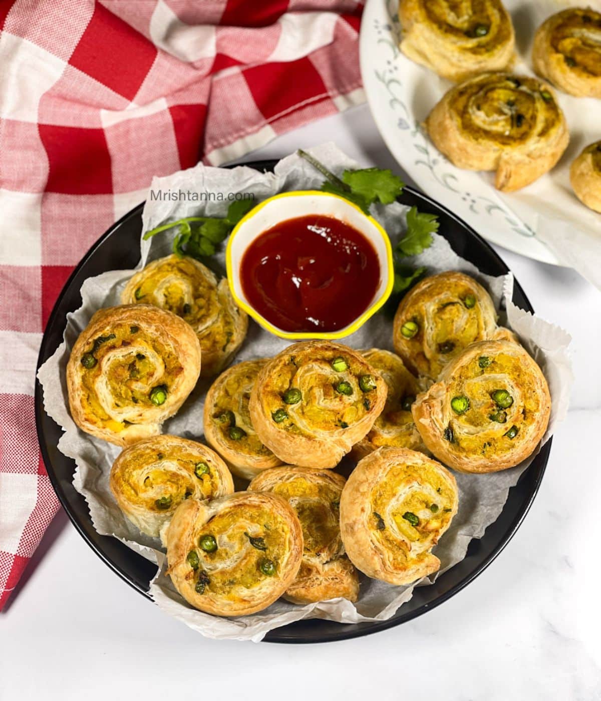 A plate of samosa pinwheels and ketchup is on the table.