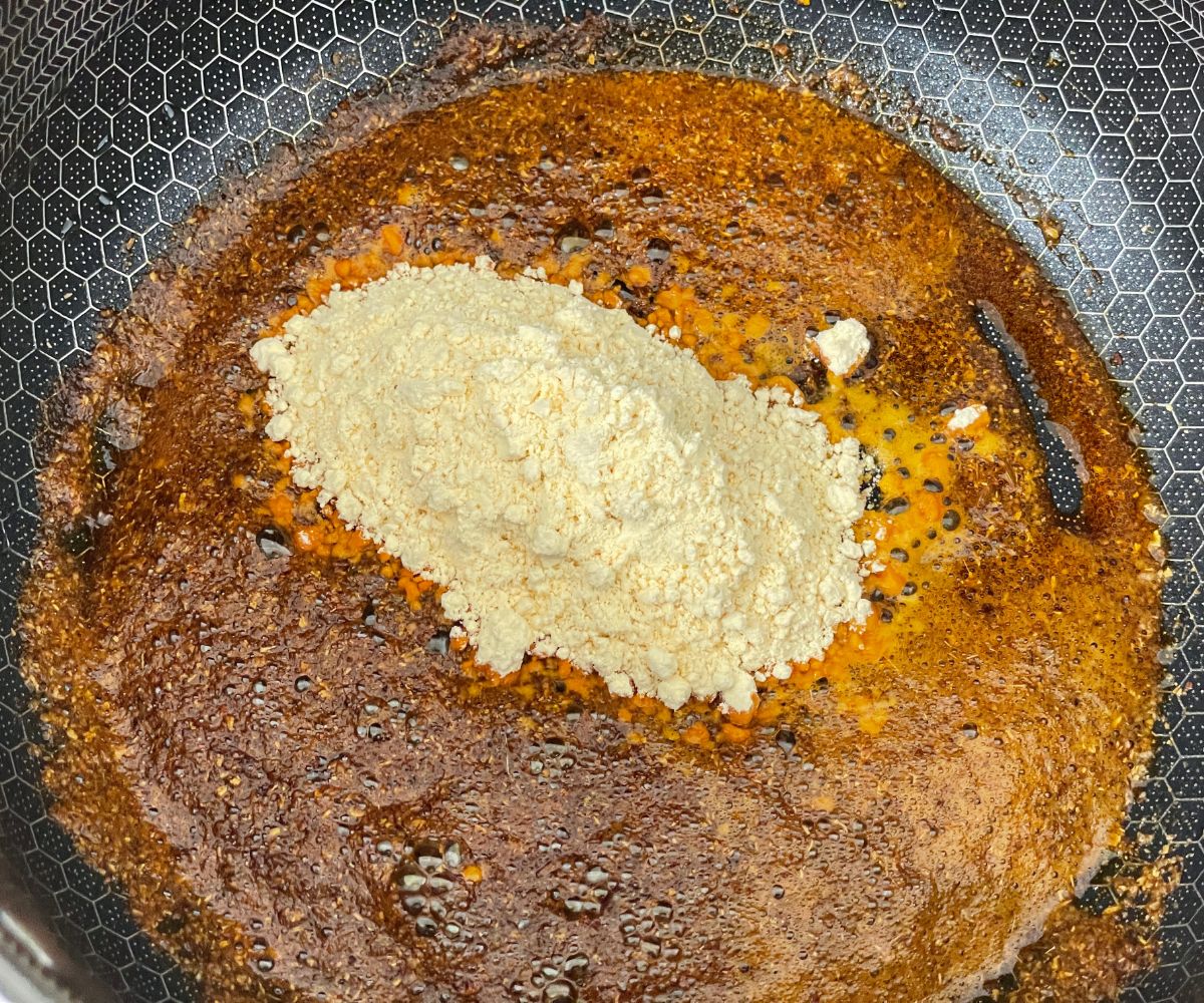 A pan is with mix of spices and besan flour over the heat.
