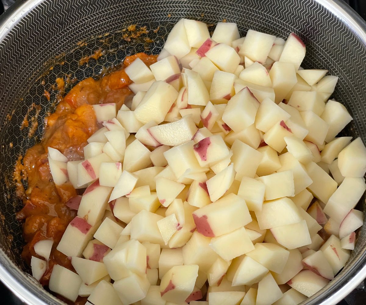 A pot is with tomatoes and potatoes over the flame.