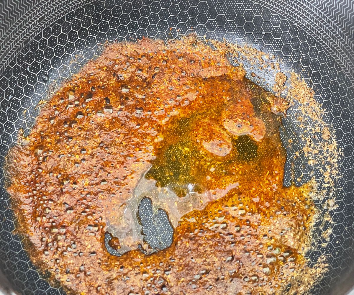 A pan is with oil, spices over the heat for potato curry.