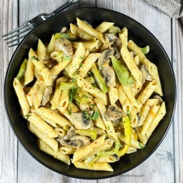 A plate of vegan Cajun Pasta is on the wooden table.