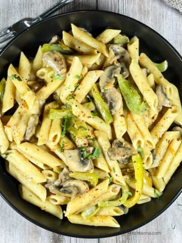 A plate of vegan Cajun Pasta is on the wooden table.