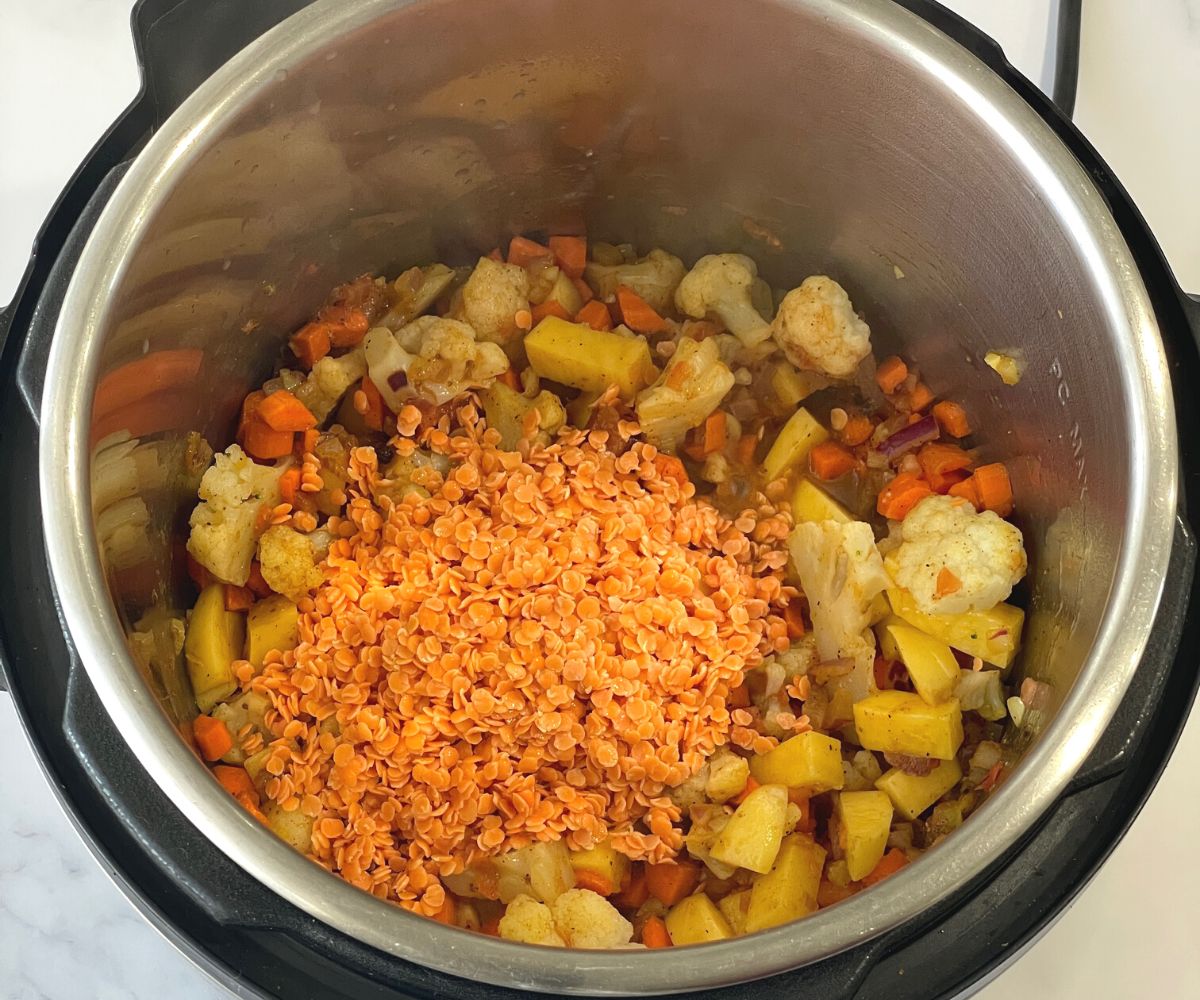 An instant pot is with vegetables, spices and lentils for mulligatawny soup.