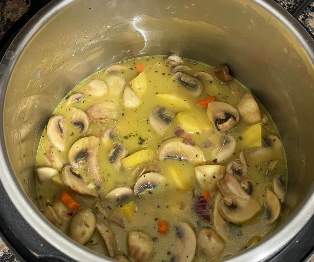 A pot is with vegan mushroom potato soup mixture on cooking mode.