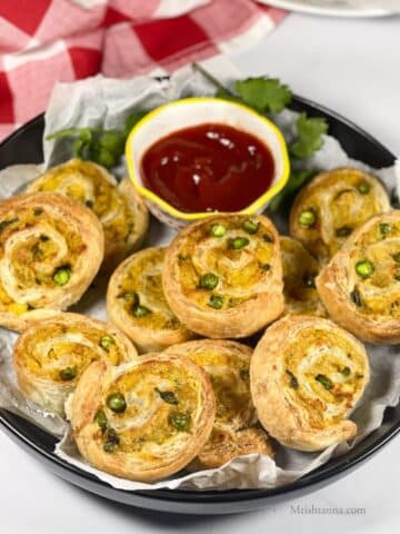 A plate is filled with air fried samosa pinwheels.