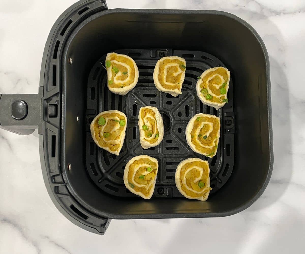 Air fryer basket is with samosa pinwheels.