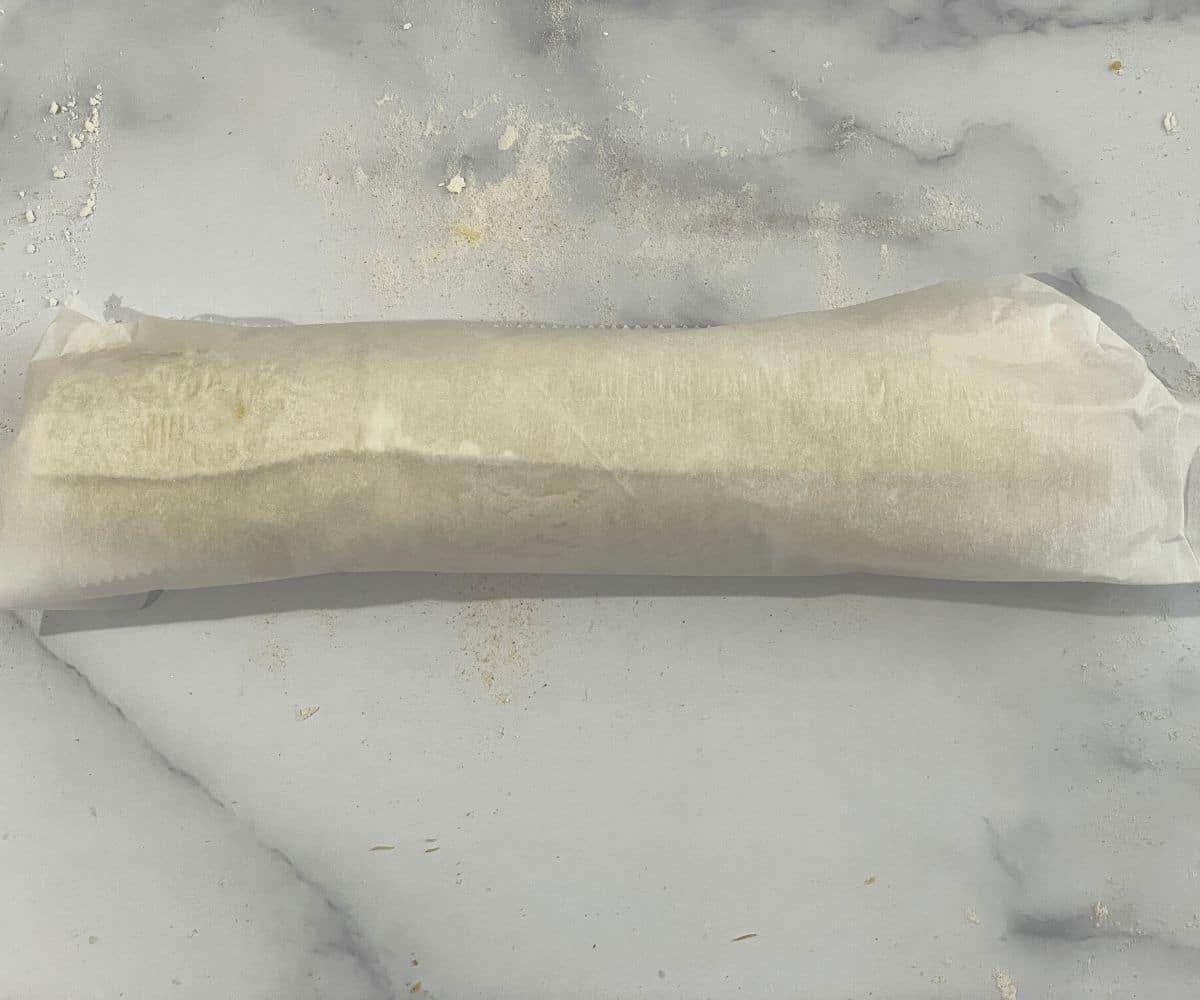 Rolled samosa pinwheel log and covered with a parchment paper.