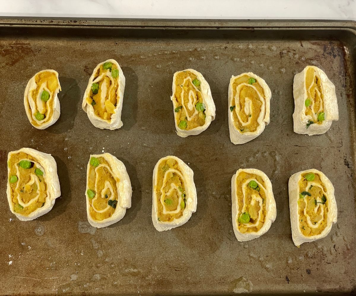 Uncooked samosa pinwheels are on the baking tray.