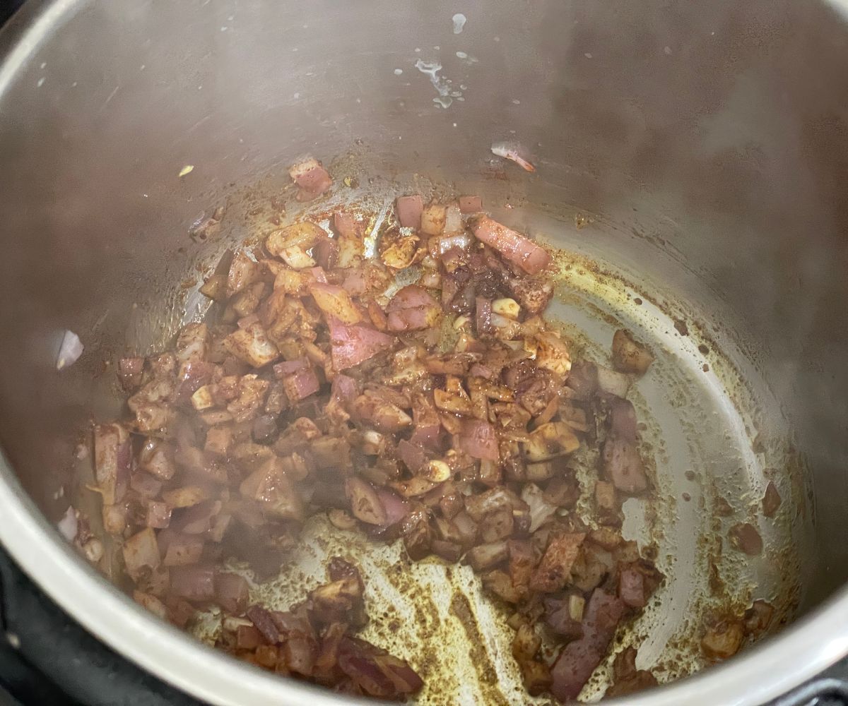 An instant pot is with onions and chili spices on saute mode.