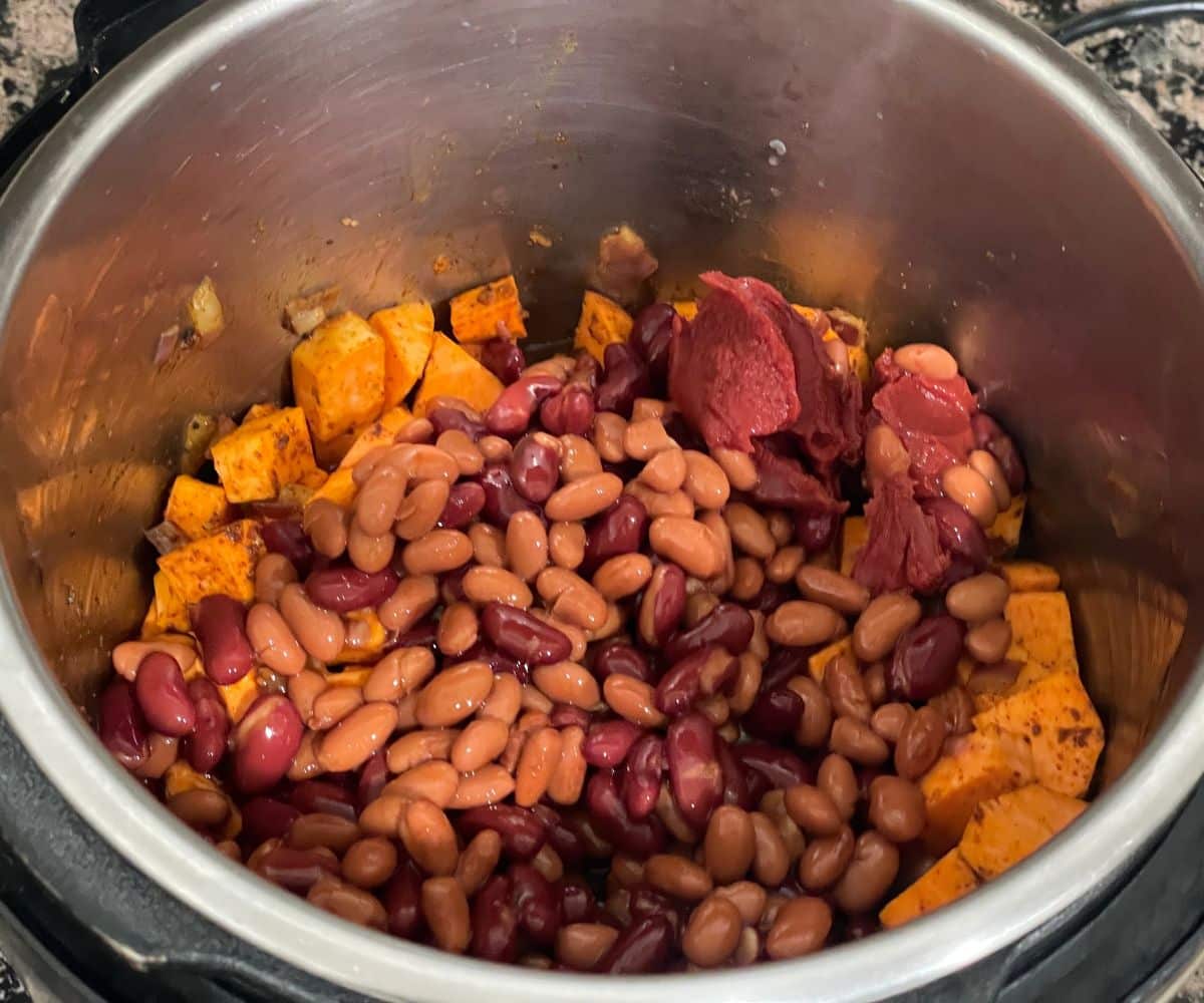 An instant pot is with sweet potato chili mixture on cooking mode.