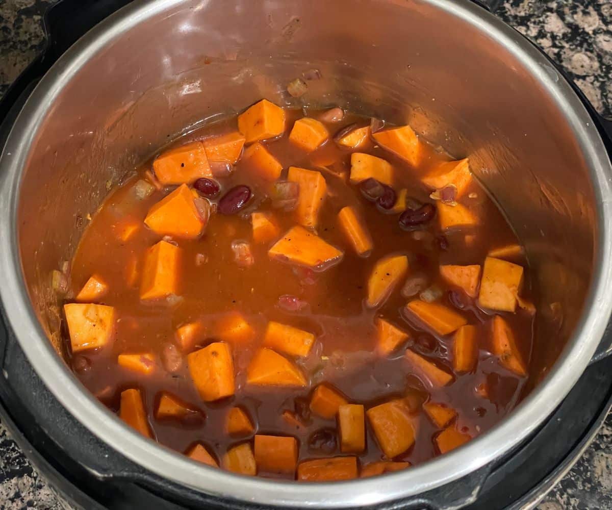 An instant pot is filled with uncooked sweet potato chili mixture.