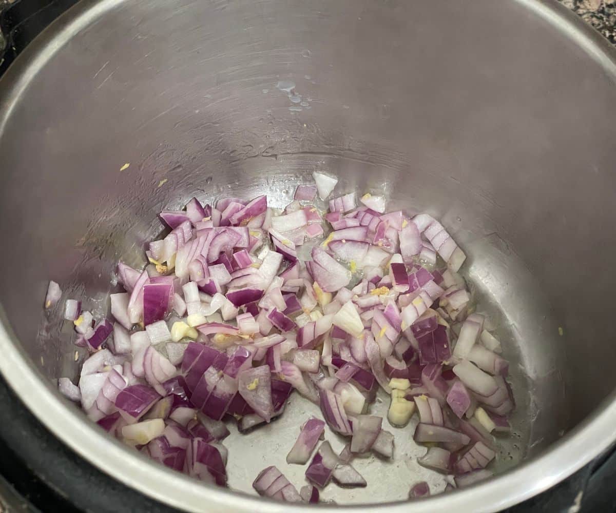 An instant pot is with chopped onions on saute mode.