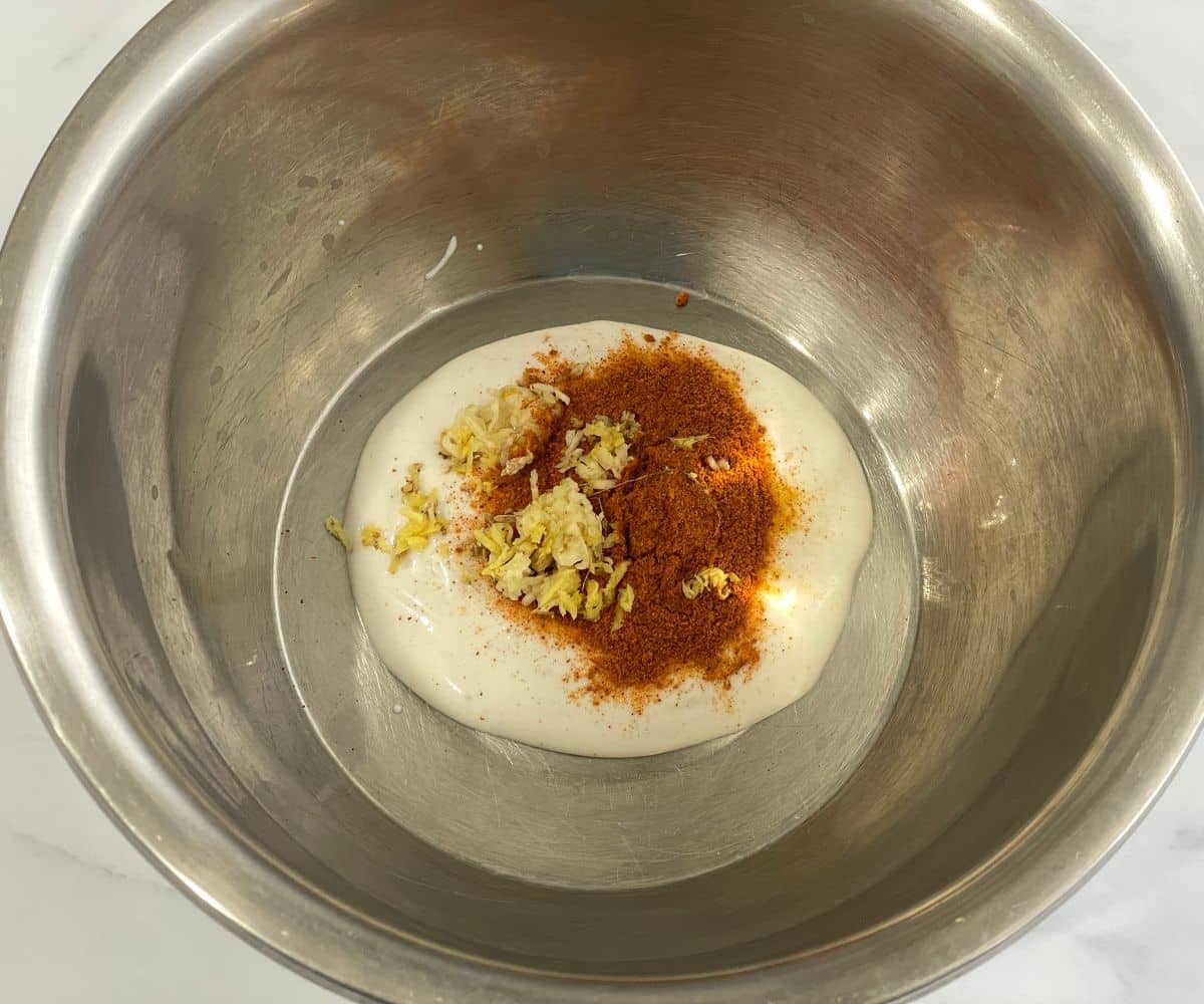 A bowl is with plant based yogurt ans spices for marinade for tandoori tofu.