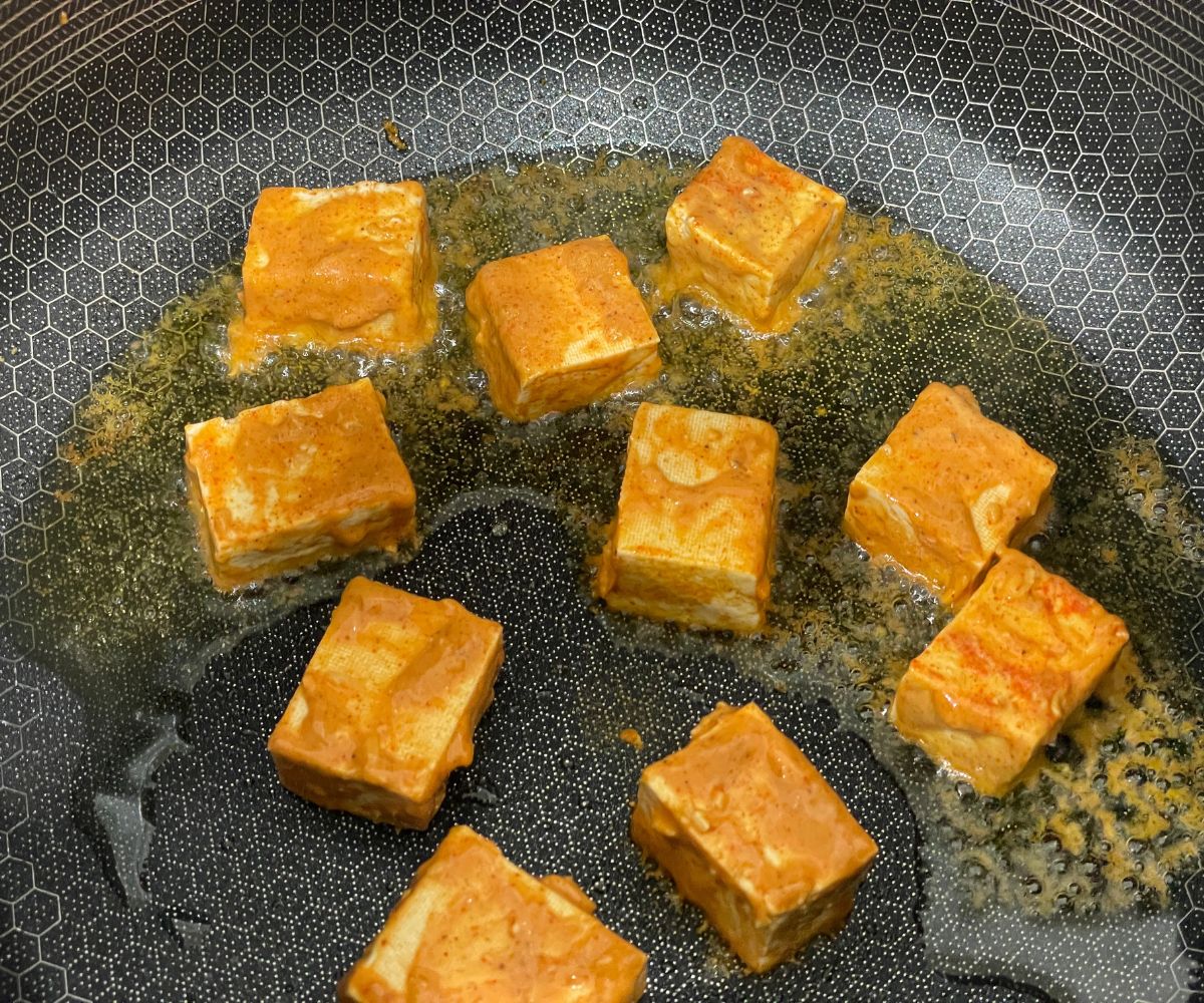 Tandoori tofu is on the tawa over the stove top.