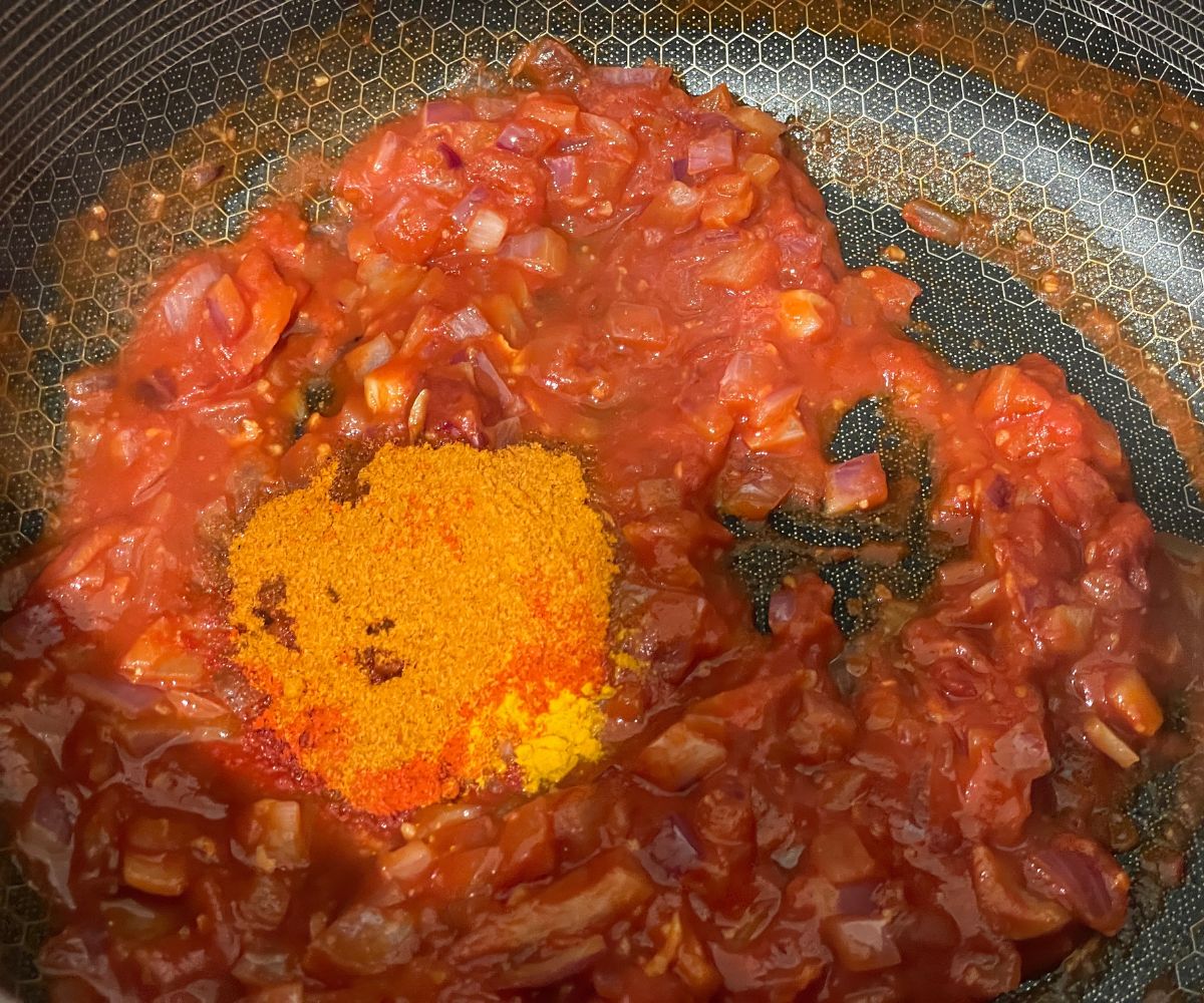 A pan is with tikka masala sauce over the stove top.