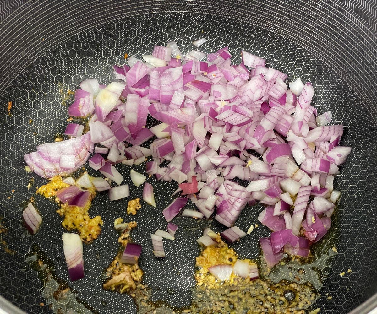 A pan is with chopped ginger, garlic and onions over the flame.