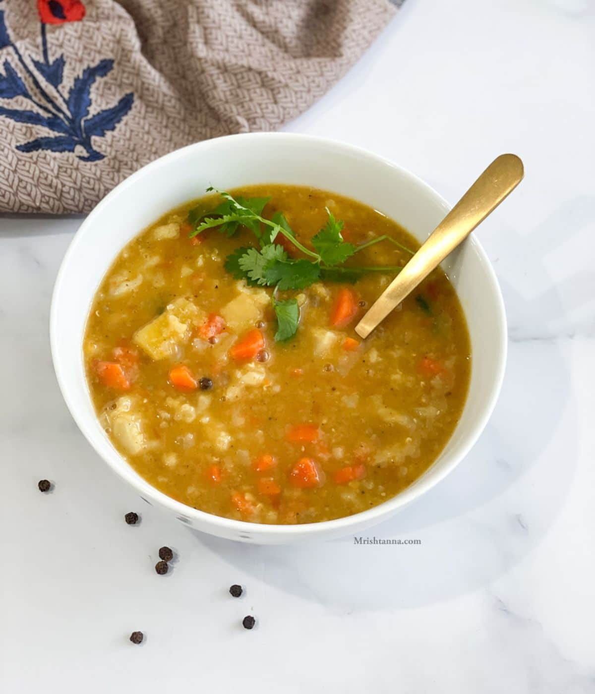 A bowl of vegan mulligatawny soup is on the table and topped with fresh cilantro.