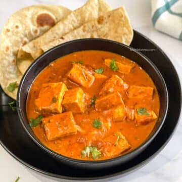 A bowl is with tofu tikka masala curry on the table.