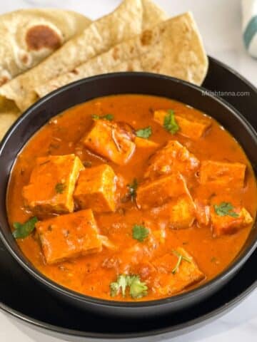 A bowl is with tofu tikka masala curry on the table.