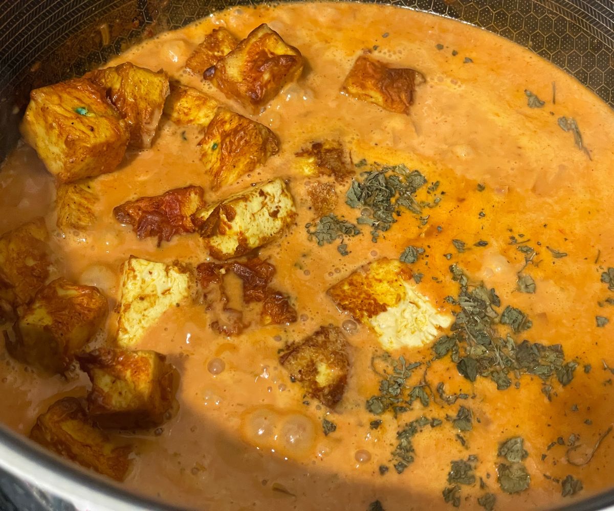 A pan is with tofu tikka masala over the heat.