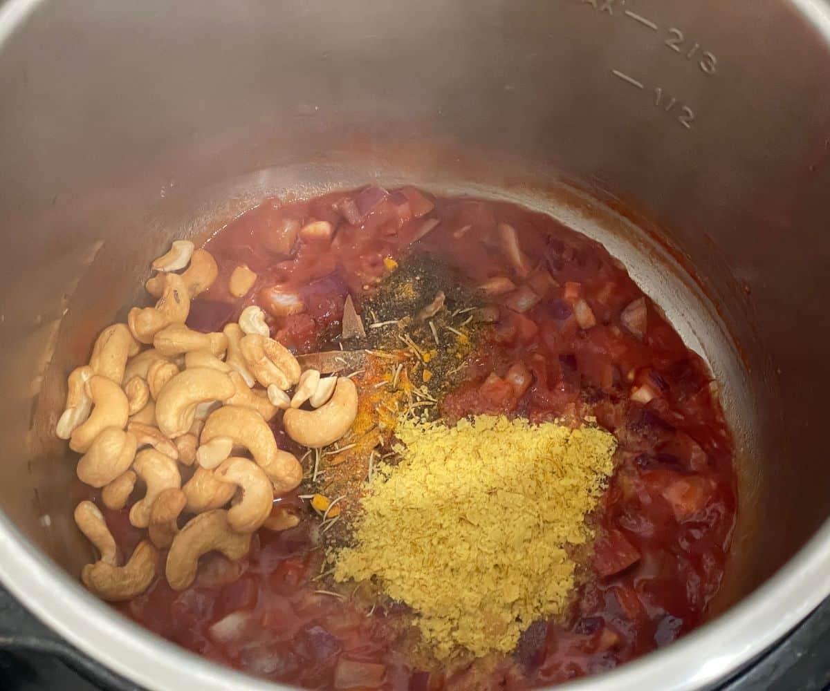 An instant pot is with spices and tomato for soup.