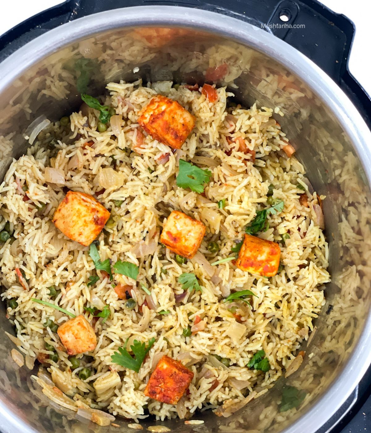 An instant pot is filled with curry rice and topped with spiced tofu.