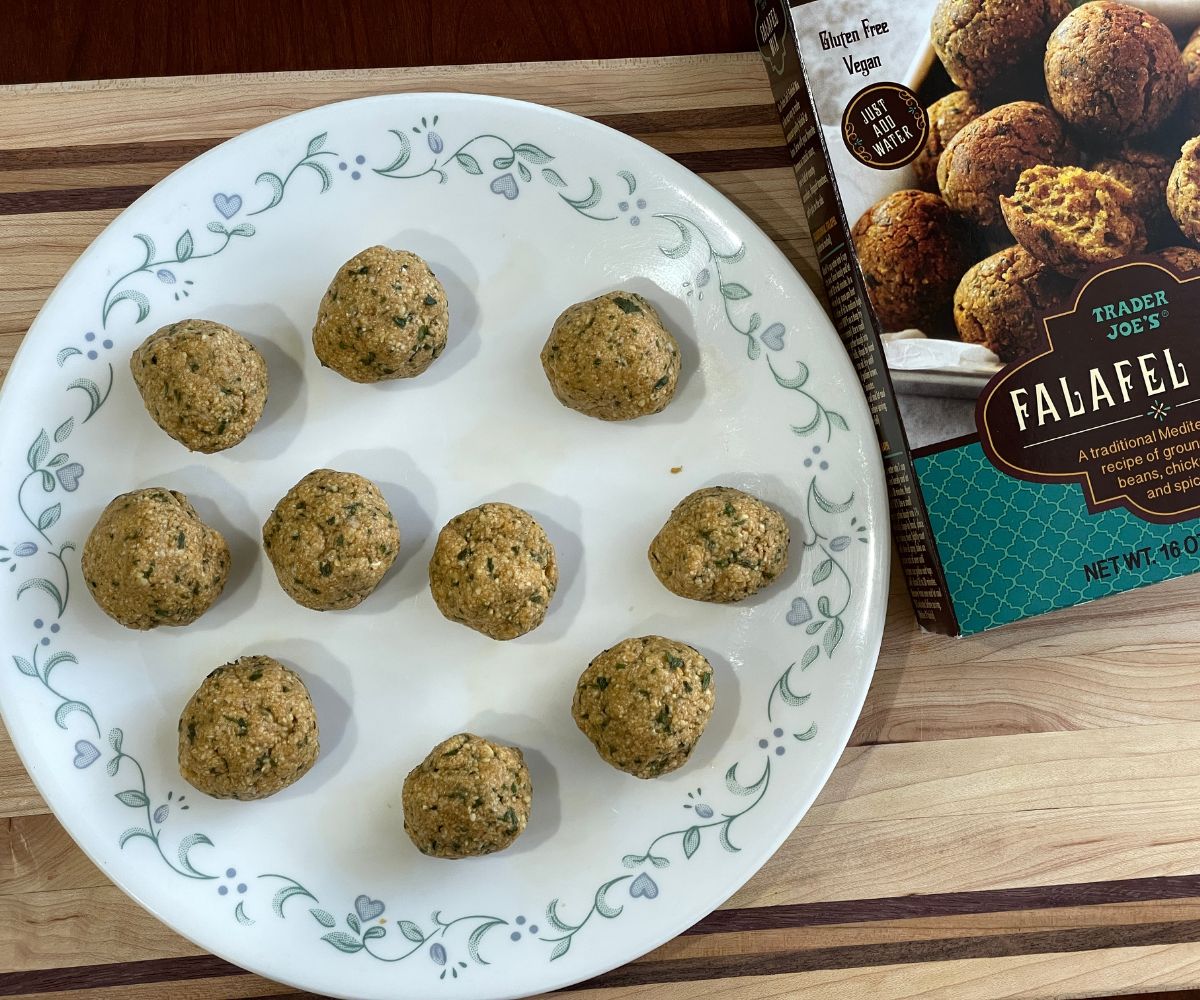 A plate is with  uncooked falafel balls on the table.